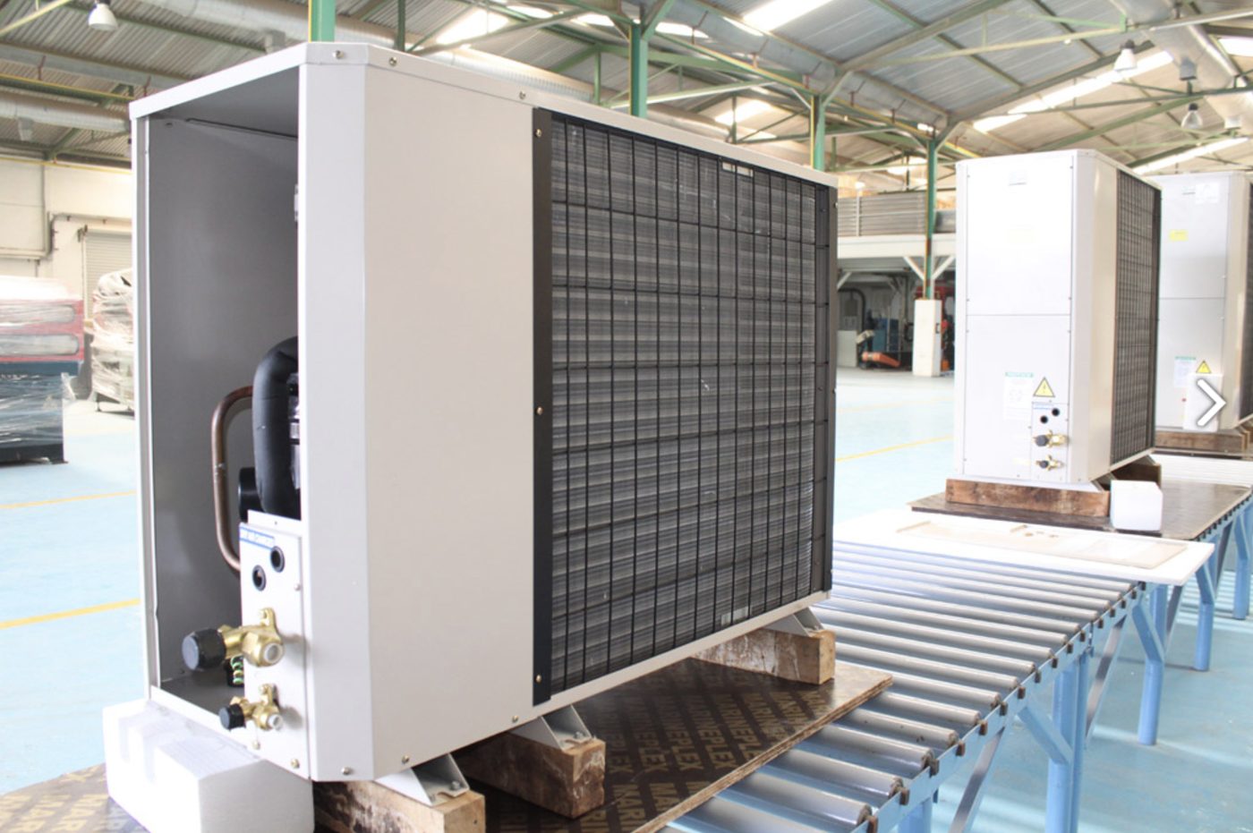 Air-cooled condensing units with copper pipework lined up in a factory